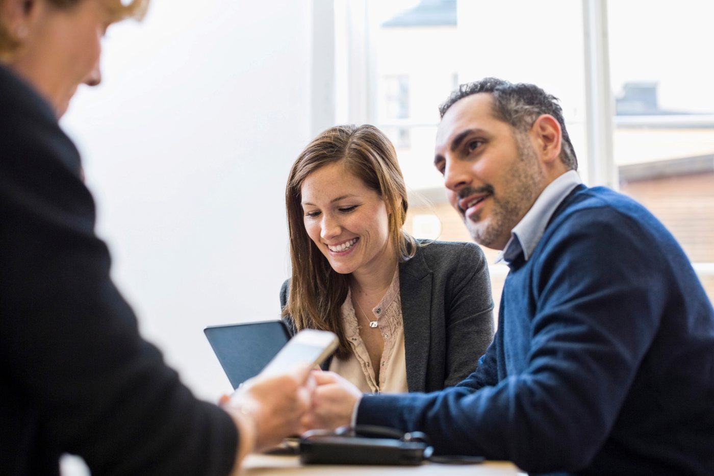 Colleagues reviewing information together on a phone and laptop